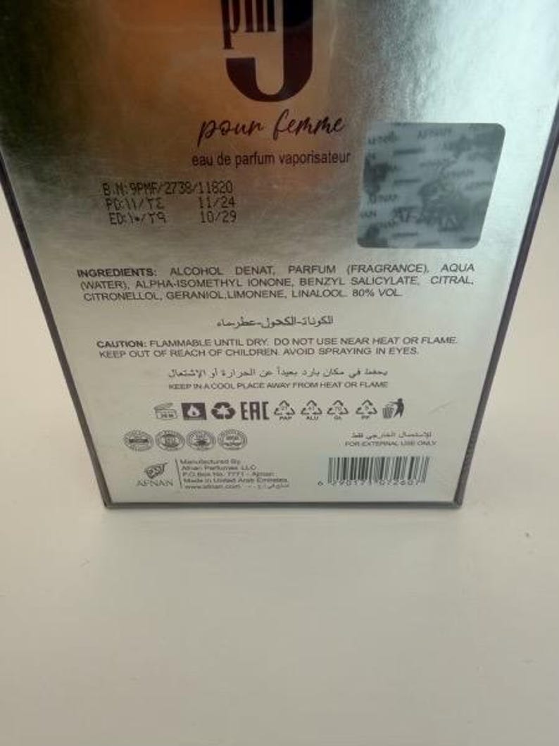 Puede incluir: Caja de perfume plateada con las palabras "pour femme" en cursiva. La caja incluye informaci&oacute;n sobre ingredientes y advertencias de seguridad. El producto es un eau de parfum vaporisateur.