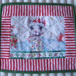 May include: Square quilted Christmas-themed pot holder. The center features a llama wearing a Santa hat and holding a candy cane, surrounded by colorful lights. The border has red and white stripes with a green trim.