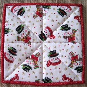 May include: Square quilted potholder with a repeating pattern of snowmen wearing black top hats, red scarves, and green and red striped mittens. The background is white with gold snowflakes and red dots. The border is red with white polka dots.