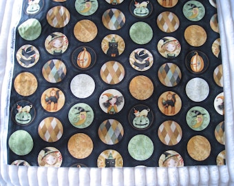 May include: A dark fabric featuring a repeating pattern of circular designs with Halloween-themed illustrations. The circles contain images of witches, black cats, pumpkins, and moons. The background is black with gold and green accents.