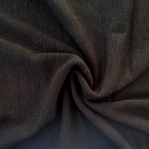 Black merino wool jersey fabric creased showing rich color saturation and drape