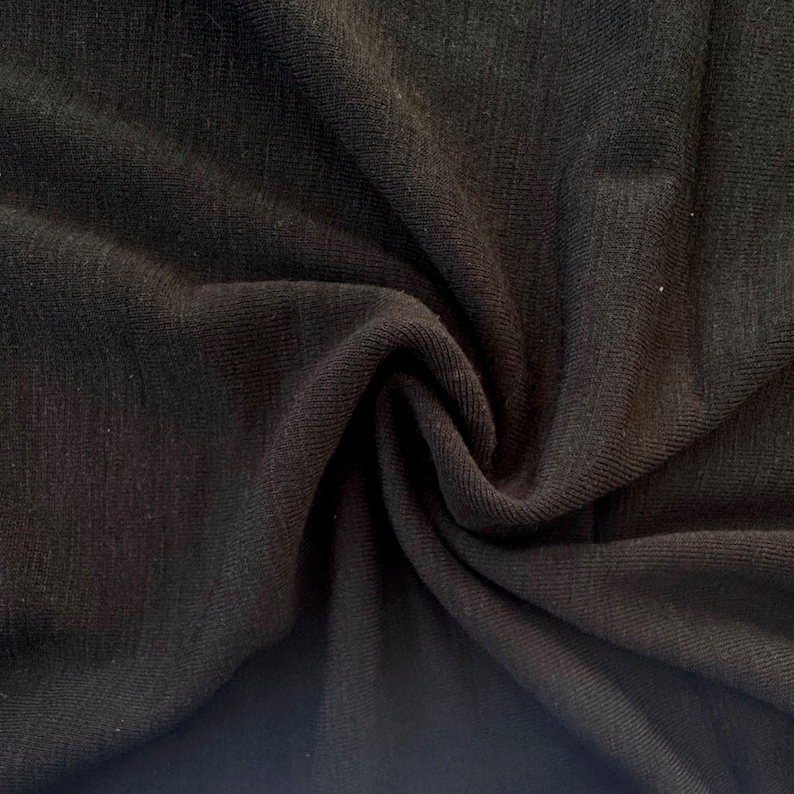 Black merino wool jersey fabric creased showing rich color saturation and drape