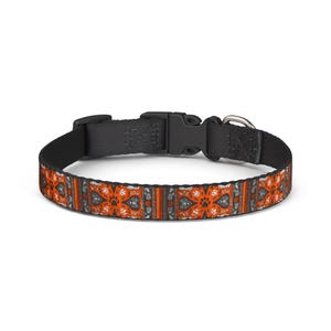 May include: A patterned dog collar with a black buckle and a silver metal loop. The collar features an orange, black, and white design with paw prints and floral patterns. The collar is approximately 1.3 cm wide.