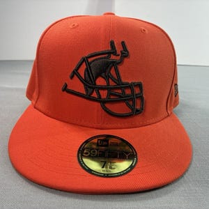 May include: Orange baseball cap with a black football helmet design. The cap has a flat brim and a fitted design. The front of the cap features a black embroidered football helmet. The cap has a 7 5/8 size label.
