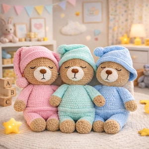 Op de afbeelding: Drie handgemaakte gehaakte teddyberen met pyjama's en nachtmutsen. De beren zijn in roze, mintgroen en blauw. Elke beer heeft gesloten ogen en een bruine neus. De beren zitten op een zacht, lichtgekleurd oppervlak.