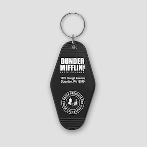 May include: A black, diamond-shaped motel-style keyring with a metal ring. It features white text reading Dunder Mifflin Inc. Paper Company, the address 1725 Slough Avenue Scranton, PA 18540, and a circular logo with the text World Paper Products.