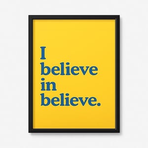 May include: A rectangular wall art print in a black frame featuring a bright yellow background with the blue text "I believe in believe." printed in a bold, serif font. The design is centered within the frame, creating a high-contrast visual.