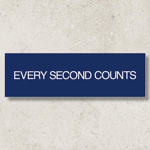 May include: A rectangular navy blue sign with the white text "EVERY SECOND COUNTS" is displayed against a textured, off-white background. The sign is centered and casts a subtle shadow.