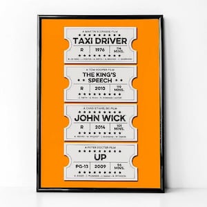 May include: A framed print with four movie ticket designs on an orange background. The tickets display film titles such as "Taxi Driver," "The King's Speech," "John Wick," and "Up," along with their release years and ratings. The frame is black.