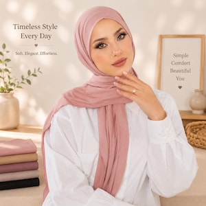 May include: A dusty rose hijab worn over a white button-down shirt. The text on the image reads: Timeless Style Every Day, Soft. Elegant. Effortless., Simple Comfort Beautiful You. A stack of folded hijabs in various neutral colours sits to the left.