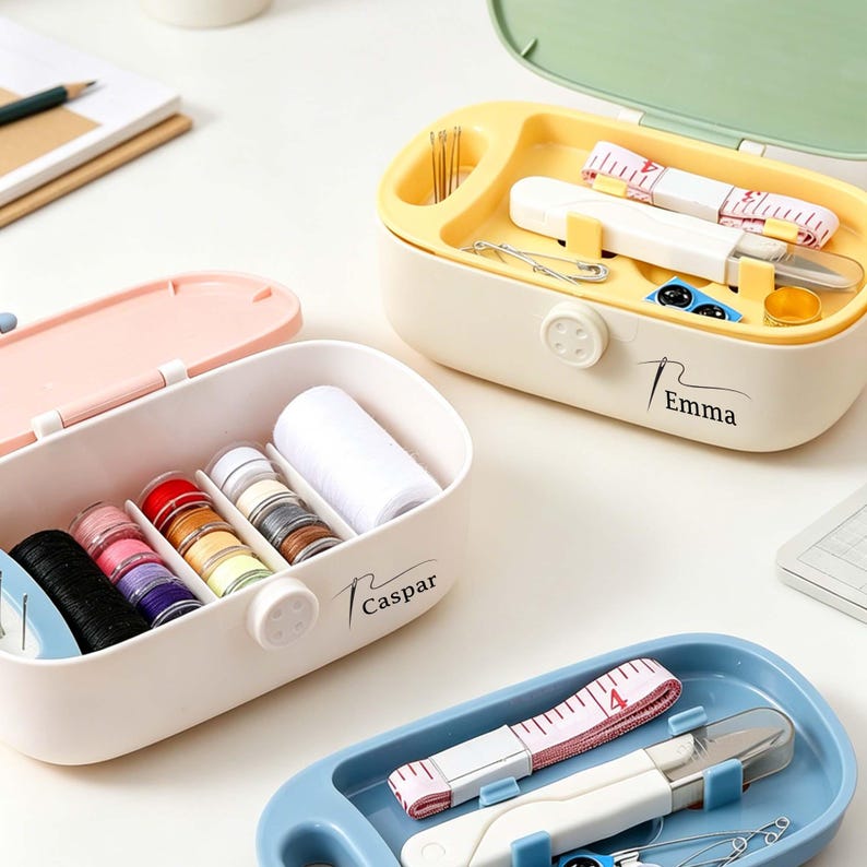 May include: Three sewing kits in pastel colors. One pink, one yellow, and one blue. The pink kit contains spools of thread and a large spool of white thread. The yellow kit has needles, scissors, and a measuring tape. The blue kit has scissors and a measuring tape.