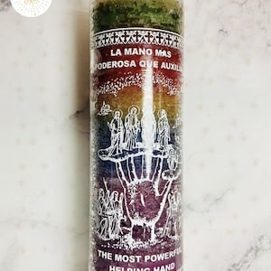 May include: A tall, multi-coloured candle with the text "LA MANO MAS PODEROSA QUE AUXILI" and "THE MOST POWERFUL HELPING HAND" in white. The candle has a layered design with green, red, yellow, blue, and purple sections. Decorative white patterns are at the top and bottom.
