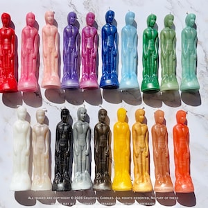 May include: A selection of figure-shaped candles in a range of colours, such as red, pink, purple, blue, green, yellow, brown, and black. The candles are arranged in rows, displaying a diverse palette of hues and tones. The candles are standing upright.
