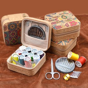 May include: A cork sewing kit with assorted needles, spools of thread, scissors, and other sewing supplies. The kit includes a variety of colorful threads and a small pair of scissors. The kit is designed for sewing and crafting.