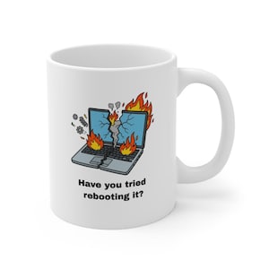 May include: A white ceramic mug with a black handle and the text "But First, Coffee" in a black, bold font. The mug is sitting on a white surface. The mug is approximately 4 inches tall.