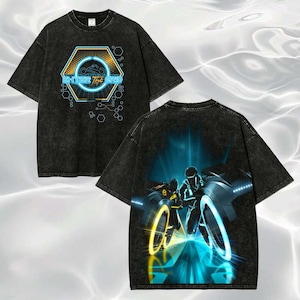May include: A black acid-wash t-shirt featuring a front graphic of a hexagon with the text "ENTER THE GRID" and a motorcycle icon. The back displays a large, vibrant illustration of two figures riding glowing light cycles on a digital path.