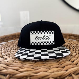 May include: Black and white checkered baseball cap with a black brim and a white patch on the front that says "Beckett" in a white script font.