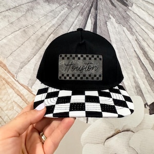 May include: Black and white checkered baseball cap with a black patch that says "Houston" in white script.