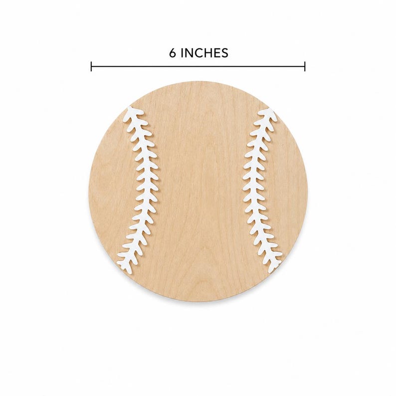 May include: A circular light-colored wooden cutout shaped like a baseball, featuring two white painted curved stitching patterns on the surface. A measurement line above the object indicates a diameter of 6 inches for the wooden baseball.
