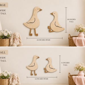 May include: Two light-colored wooden duck wall decorations featuring a standing duck and a sitting duck. The large set measures 24 inches wide by 18 inches tall. The small set measures 14 inches wide by 11 inches tall. The ducks have simple black line details.