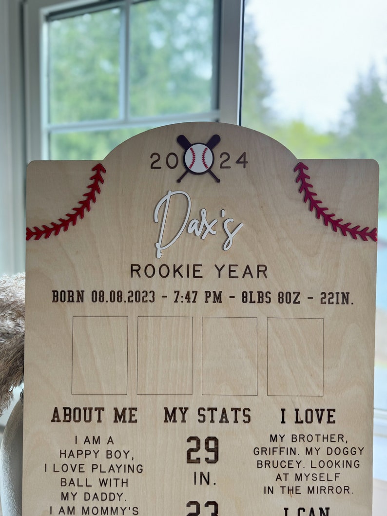 May include: A wooden sign with a baseball theme, announcing a baby's "Rookie Year." The sign includes the baby's name, "Dax's," birthdate, time, weight, and length. The sign also includes the text "About Me," "My Stats," and "I Love." The sign is decorated with red stitching and a baseball and bats.