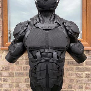 May include: A black, futuristic-looking torso armor set. The armor features detailed paneling, shoulder pads, and a neck piece. The design suggests a high-tech or science fiction theme, with a focus on protection and a sleek aesthetic.