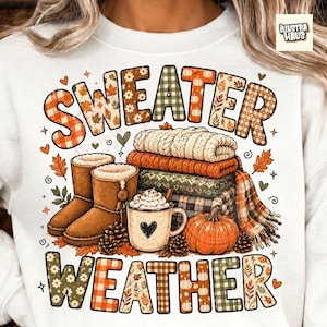 Puede incluir: Una sudadera blanca con un gráfico que incluye el texto SWEATER WEATHER. El diseño muestra una pila de jerséis doblados, dos botas marrones, una taza con nata y un corazón, una calabaza, piñas y hojas de otoño en tonos naranja y verde.