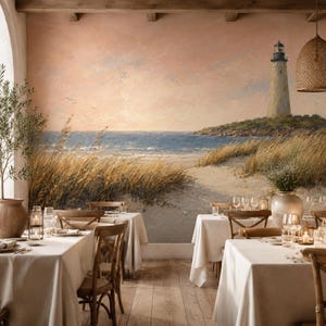 Peut inclure: Une peinture murale représentant une scène côtière avec un phare sur une pointe rocheuse, des herbes de plage dorées et un océan bleu calme sous un ciel pêche doux. La peinture est exposée dans une salle à manger avec des nappes blanches.