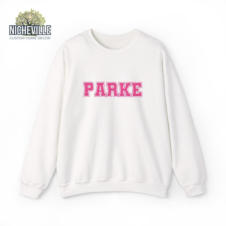 White Gildan 18000 sweatshirt with pink varsity PARKE text embroidery style design, front view studio mockup showing personalized custom name sweatshirt, Nicheville custom sweatshi