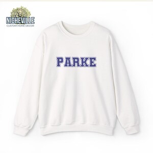 White Gildan 18000 sweatshirt with blue varsity PARKE text design, clean front view product mockup showing custom name sweatshirt personalization, Nicheville custom apparel example