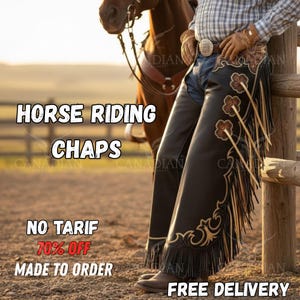 May include: Black leather horse riding chaps with decorative floral and scrollwork embroidery. The chaps have fringe along the sides. The text "HORSE RIDING CHAPS" is displayed. A person is leaning against a wooden fence wearing the chaps.