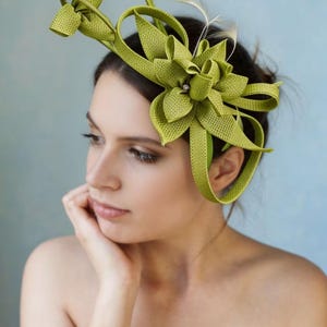 Op de afbeelding: Een limoengroene haarversiering met een bloemenontwerp en veermotieven. De haarversiering heeft een grote bloem en lussen, perfect voor speciale gelegenheden. De vrouw op de foto draagt de haarversiering.