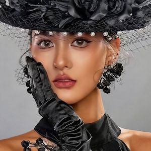 May include: A black hat decorated with fabric roses and a fine veil, with pearls along the brim. The image also features matching black gloves and earrings with floral details. The overall style is gothic and elegant, suitable for special occasions.