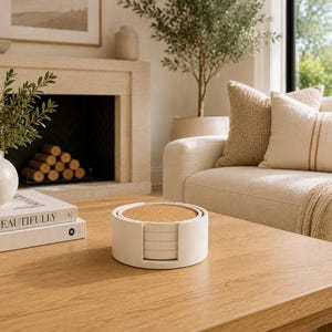 May include: A set of round drink coasters featuring a natural cork top surface and a white circular holder. The coasters are stacked vertically within the holder, which has a cutout design on the side to allow for easy access to the individual pieces.