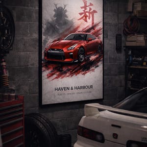 Könnte beinhalten: Ein gerahmtes Poster mit einem roten Sportwagen, japanischen Schriftzeichen und einer Samurai-Silhouette. Das Poster befindet sich in einer Garage mit dem Text "HAVEN & HARBOUR" und "OBJECTS - SPACES - VISUAL CULTURE".