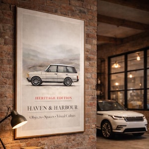 May include: A framed print featuring a vintage white SUV with the text "HERITAGE EDITION HAVEN & HARBOUR Objects • Spaces • Visual Culture." The print hangs on a brick wall. A white SUV is parked in the background.