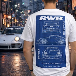 May include: White t-shirt with a blue graphic featuring car blueprints and the text "RWB" and "HAVEN & HARBOUR". The shirt is worn by a person standing in front of a white sports car on a city street.