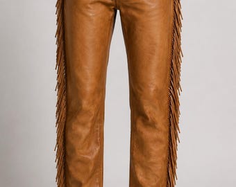 May include: Tan leather pants featuring a straight-leg cut, a button closure at the waist, and long, thin fringe detailing running down the entire length of the outer side seams on both legs, creating a textured appearance along the edges.