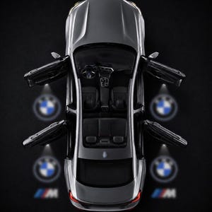 Puede incluir: Una vista cenital de un sedán gris con las cuatro puertas abiertas. Cada puerta proyecta un logotipo circular de BMW en el suelo, y las puertas traseras también proyectan el logotipo M. El interior cuenta con asientos negros, volante y consola.
