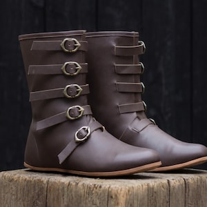 Może przedstawiać: Biały ceramiczny kubek z czarnym uchwytem i napisem "But First, Coffee" czarną, odręczną czcionką. Kubek stoi na białej powierzchni.