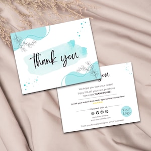 May include: Two white cards with a light blue watercolor design and the words "Thank you" in black script. One card is face up, the other is partially visible, with text about a discount and social media handles.