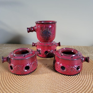 May include: A set of three ceramic mugs with a speckled, matte finish. The mugs are in shades of cream, light gray, and dark gray. Each mug has a simple, minimalist design and a rounded handle.