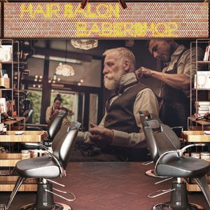 Può includere: Interno di un barbiere con un cliente che si fa tagliare i capelli. Il negozio presenta poltrone da barbiere nere, scaffali in legno con prodotti e un'insegna che recita "HAIR SALON BARBERSHOP". Il cliente ha la barba bianca e indossa un gilet.