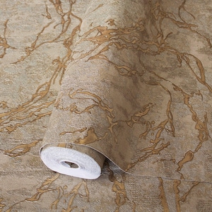 Könnte beinhalten: Eine Tapetenrolle mit einem strukturierten beigen und hellbraunen Hintergrund und einem erhabenen, metallisch goldenen, marmorartigen Adernmuster. Die Oberfläche weist eine sichtbare gewebeartige Textur auf, wobei die goldenen Adern ein verzweigtes Design bilden.