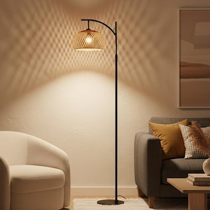 May include: A modern living room scene featuring a black floor lamp with a woven shade, a white armchair, and a gray sofa with decorative pillows. A potted plant and a small side table complete the cozy interior.