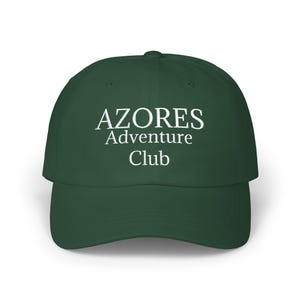 May include: A dark forest green baseball cap featuring the white embroidered text "AZORES Adventure Club" centered on the front panel. The cap has a structured crown, a curved brim, and a button at the top center of the dome.