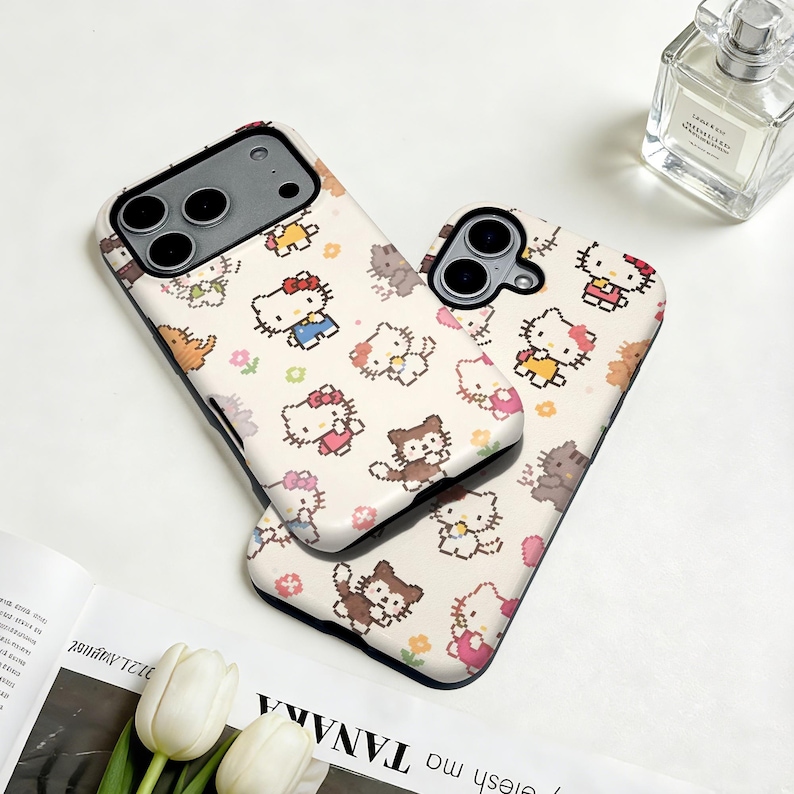 May include: Two phone cases with a repeating pattern of cartoon cats and other characters in various outfits and poses. The cases are white with black edges. The design includes characters with red, pink, yellow, and blue clothing. The cases are on a white surface.