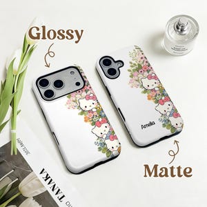 Puede incluir: Dos fundas blancas para tel&eacute;fono con un dise&ntilde;o floral y de gato de dibujos animados. Una funda est&aacute; etiquetada como "Glossy" y la otra como "Matte". Las fundas presentan un colorido arreglo floral y el personaje de gato de dibujos animados.