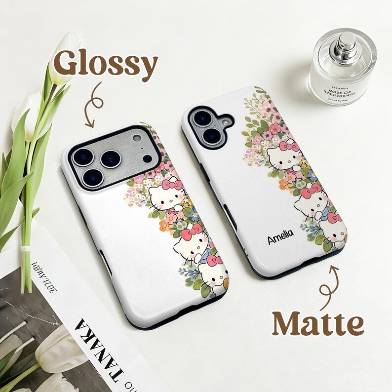 Puede incluir: Dos fundas blancas para tel&eacute;fono con un dise&ntilde;o floral y de gato de dibujos animados. Una funda est&aacute; etiquetada como "Glossy" y la otra como "Matte". Las fundas presentan un colorido arreglo floral y el personaje de gato de dibujos animados.