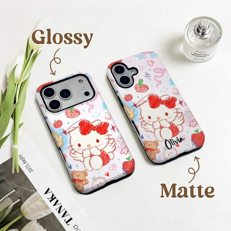 Puede incluir: Dos fundas de tel&eacute;fono con fondo blanco con un gato de dibujos animados con un lazo rojo, alas de &aacute;ngel y un osito de peluche. Una funda es brillante y la otra mate. La palabra "Olivia" est&aacute; escrita en una funda.